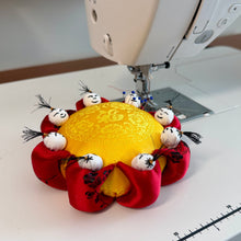 Load image into Gallery viewer, Sewing machine with a yellow fabric circle and red circular piece with small black and white figures on a white surface. Vintage pincushion