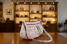 Load image into Gallery viewer, Floral-patterned handbag on a wooden surface with a vase of flowers in the background