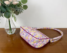 Load image into Gallery viewer, Floral-patterned bag on a wooden surface with a vase of flowers in the background