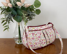 Load image into Gallery viewer, Floral-patterned handbag on a wooden surface with a vase of flowers in the background
