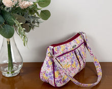 Load image into Gallery viewer, Floral-patterned handbag next to a vase with flowers on a wooden surface
