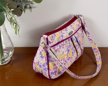 Load image into Gallery viewer, Floral-patterned handbag on a wooden surface with a vase of flowers next to it.
